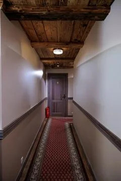 Rustic corridor with wooden door, patterned runner, and warm light Stock Photos