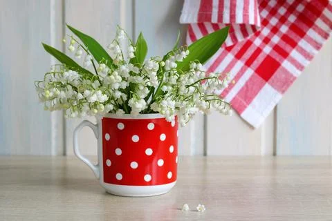 Rustic cottage kitchen still life with lily of valley flowers in red polka .. Fotos de archivo
