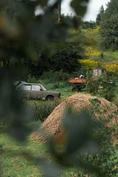 A rustic courtyard. A haystack. In the background is an old car and a tractor Stock Photos