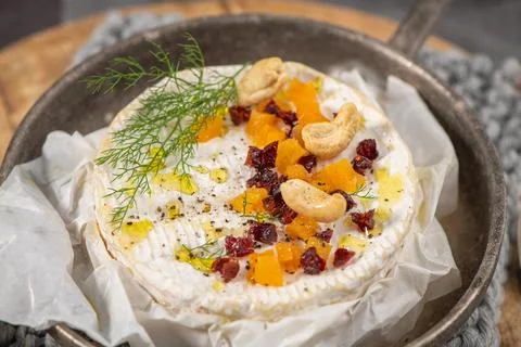 A rustic culinary display of warm baked camembert topped with dried apricot.. Stock Photos