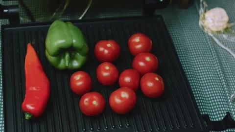 Rustic culinary view of tomatoes and peppers heating on ridged cast iron Stock Footage 342152651