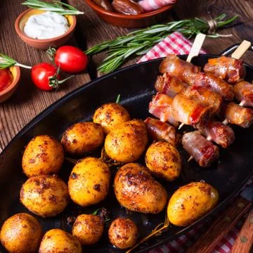 Rustic dates wrapped in bacon and young roasted potato. Stock Photos