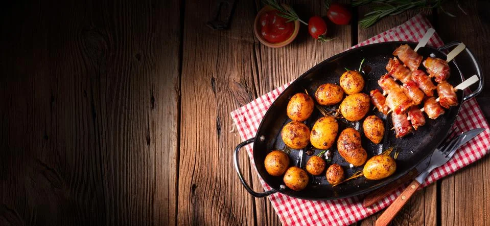 Rustic dates wrapped in bacon and young roasted potato. Stock Photos