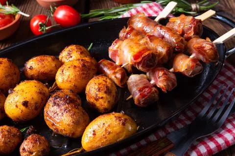 Rustic dates wrapped in bacon and young roasted potato. Stock Photos