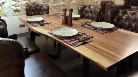 Rustic dining interior with long wooden table, brown tufted leather chairs 스톡 동영상 343628442
