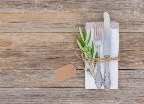 Rustic dinner menu table place setting napkin, silver cutlery, olives twig Stock Photos