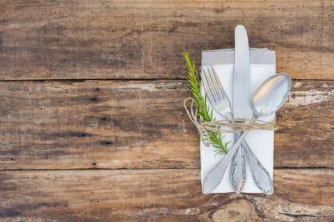 Rustic dinner menu table place setting with napkin, silver cutlery, rosemary Stock Photos