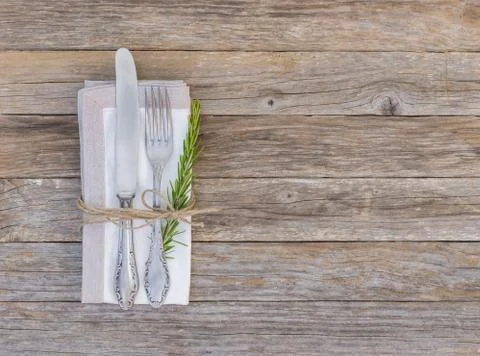 Rustic dinner menu table setting with napkin, silver cutlery and rosemary Stock Photos