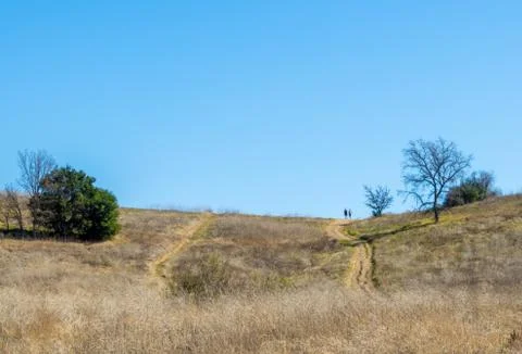 Rustic dirt path with two people hiking in the distance in Malibu, California Stock Photos