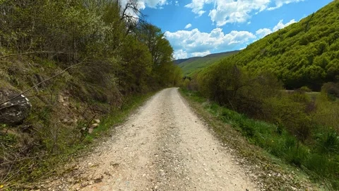 Rustic dirt path winds through lush green hills. Near Tupavica Waterfall Stock-Footage 335532255