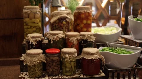 Rustic display of assorted pickled vegetables in glass jars with burlap covers a Stock Footage 310536997