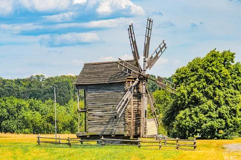 Rustic Dutch windmill in a grassy field, surrounded by trees The weathered st Stock Photos