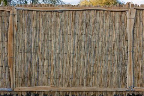 Rustic fence made of wicker straw mat Stock Photos