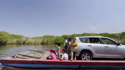 Rustic ferry carrying two vehicles and some people on the Canal de Chiquimulilla Stock Footage 182624094