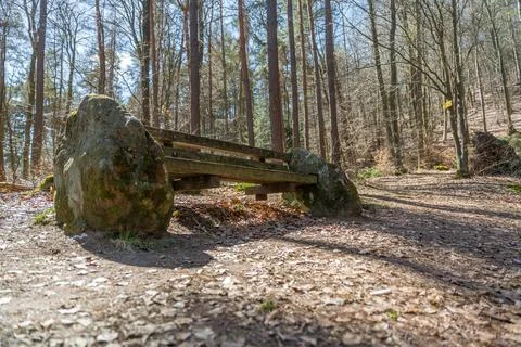 Rustic Forest Bench Between Mossy Rocks Along A Woodland Trail In Sunlit Spring Stock Photos