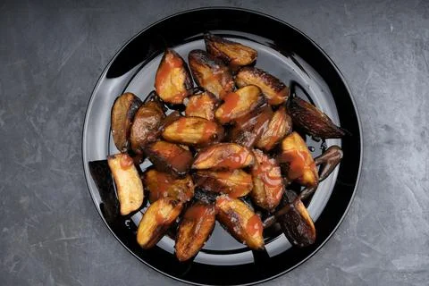 Rustic fried potatoes on a black dish on the table Stock-Fotos