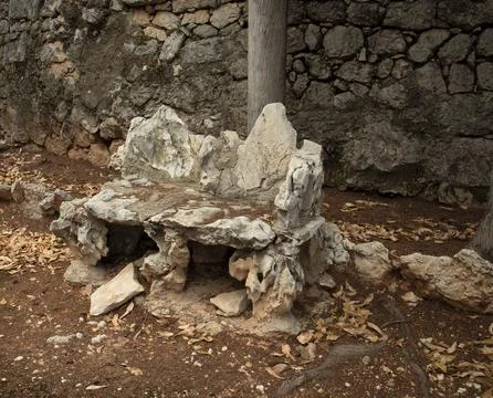 Rustic garden bench made from rough limestone rocks set against a dry stone.. Stock-Fotos
