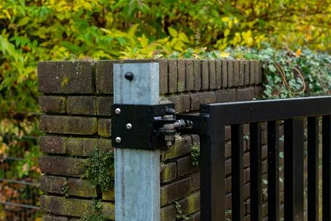 Rustic garden gate hinge mounted on brick wall in autumn setting Stock Photos