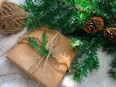 Rustic gift on white snow background with fir branches and pine cones. Stock Photos