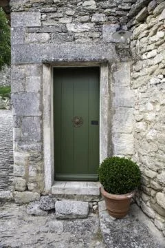 Rustic Green Door in Stone Wall With Potted Boxwood Beside Cobblestone Alle.. Stock Photos