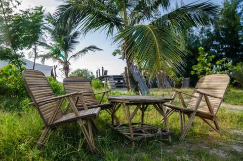 Rustic group of chairs and table made of bamboo in lush green surroundings at Stock Photos