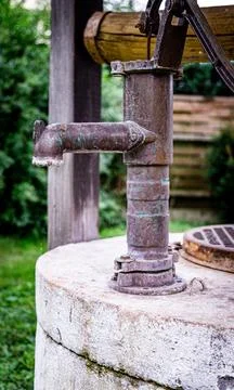 Rustic Hand Pump on a Well in a Lush Garden Stock Photos