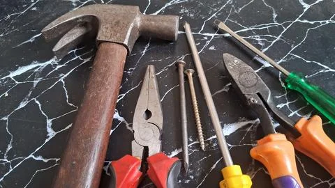 Rustic hand tools hanging on a fence. Vintage construction equipment for repair Stock Photos