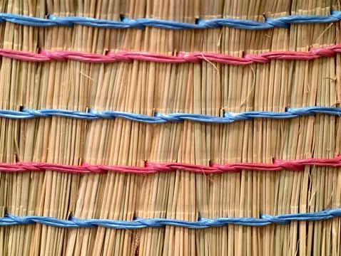 Rustic handcrafted mat with vibrant threads, sustainable natural straw material Stock Photos