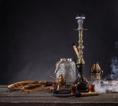 Rustic handmade hookah and arabic tea for relaxation in a dark moody room, ru Stock Photos