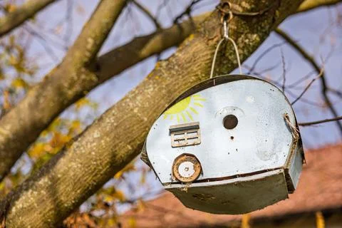 Rustic Hanging Birdhouse On Tree Branches With Weathered Metal Look And Sun.. Foto stock