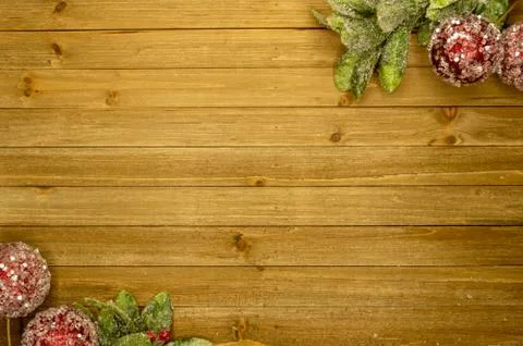 Rustic holiday wood plank background with frosted leaves and red ball ornaments Stock Photos
