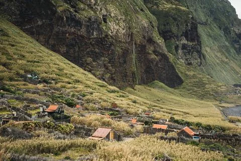 Rustic homes nestled on a steep, vegetated hillside, with dramatic cliff fa.. Stock Photos