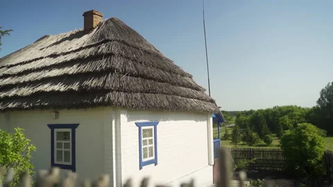 A rustic house with a chimney and white walls, standing next to a forest. Video stock 231756538
