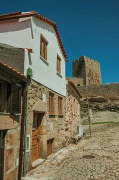 Rustic house in front of stone wall and square tower Stock Photos