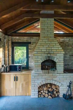Rustic indoor fireplace with a brick chimney and wood storage, creating a Stock Photos