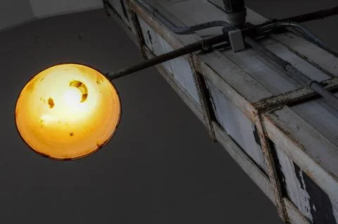 Rustic industrial ceiling light casting warm glow in minimalist setting Stock Photos
