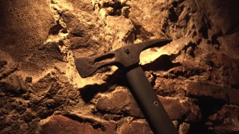 Rustic iron hammer with worn wooden handle leaning against textured stone wall Stock Footage 335762646