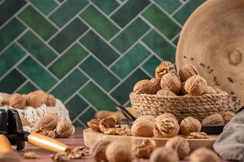 Rustic kitchen scene featuring walnuts in a woven basket on a wooden board .. Stockfoto's