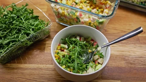 Rustic kitchen scene with fresh arugula in plastic container, creamy surimi Stock Footage 306602666