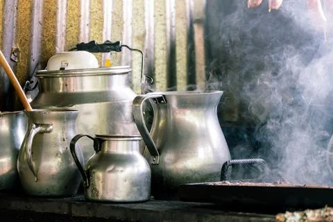 Rustic kitchen scene with steaming metal jugs and kettles on a stove Stock Photos
