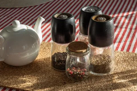 A rustic kitchen scene with a white teapot and peppercorns, spices, and gri.. Foto stock