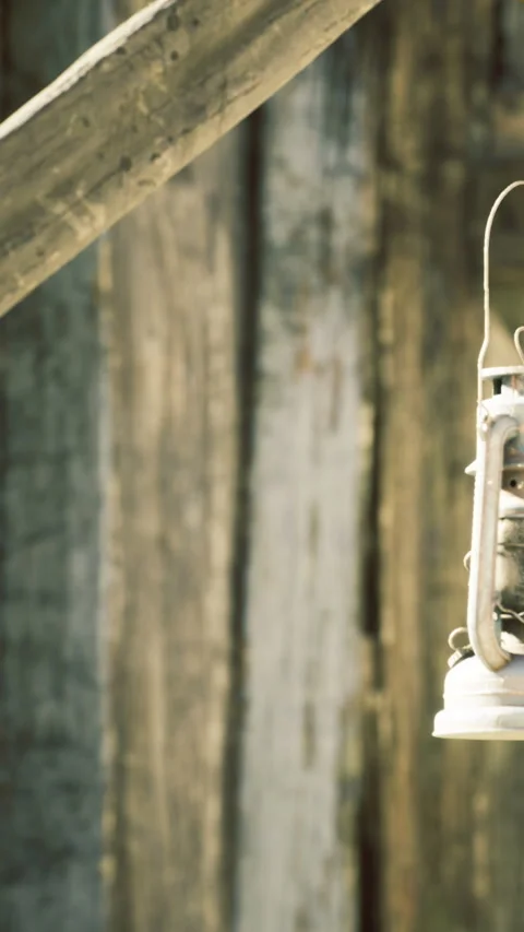 Rustic lantern casting warm glow in an old wooden barn during twilight hours Stock Footage 331841214