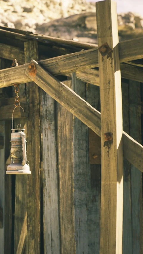 Rustic lantern hanging from weathered wooden structure in warm sunlight Stock Footage 331832993