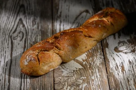 Rustic loaf of artisan bread resting on a weathered wooden table in soft li.. Stock Photos