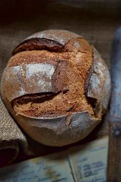 A rustic loaf of bread with an old cookbook and a knife Stock Photos
