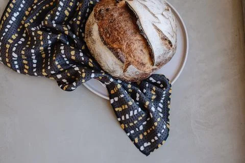 Rustic loaf of bread on a plate with a patterned cloth 写真素材