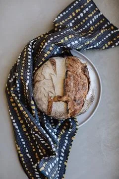 Rustic loaf of bread on a plate with a patterned cloth Stock Photos