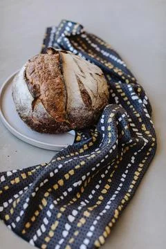 Rustic loaf of bread on a plate with a patterned  cloth Stock Photos