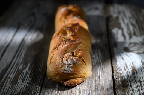 Rustic loaf of bread resting on weathered wooden table under soft light Stock Photos