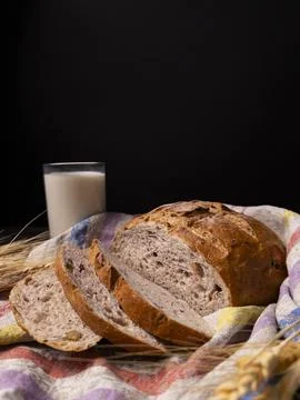 A rustic loaf of bread sliced and served with a glass of milk 스톡 사진